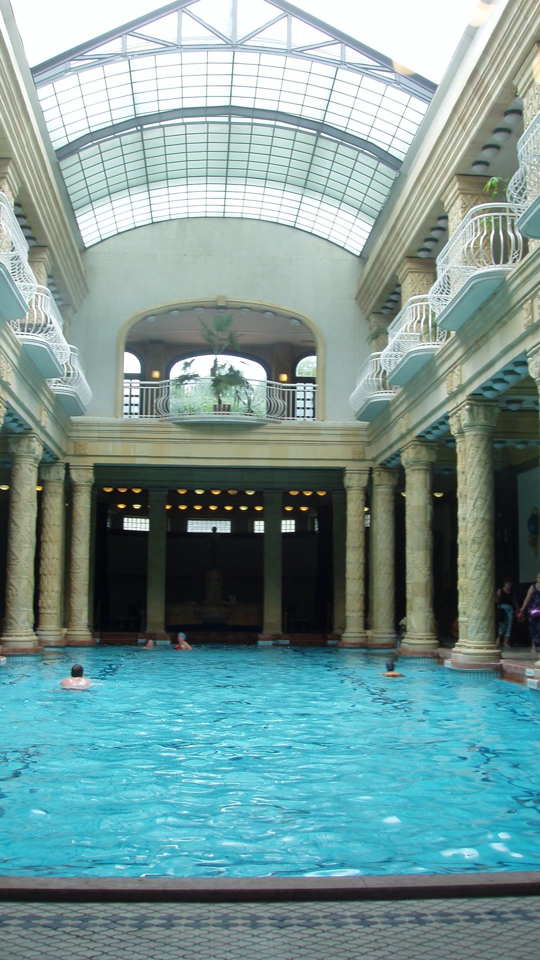 The indoor pool at Gellért Baths, under a glass roof and a row of columns.